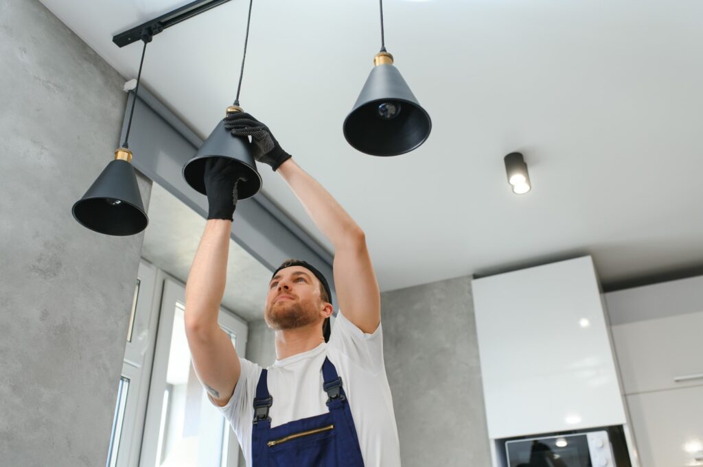 A handyman installing a new light fixture in a home for improved lighting.